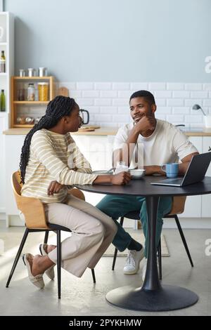 Vertical image of young couple having breakfast together sitting at table in the kitchen Stock Photo