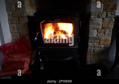 wood and coal multi fuel stove heating in a cottage with stone fireplace in county donegal republic of ireland Stock Photo