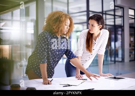 Working hard to make their designs come to life. two young architects working on blueprints in an office. Stock Photo