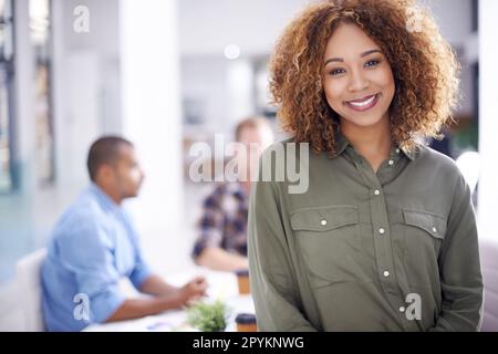 Dont chase trends - set your own. Portrait of a young designer standing in an office with her colleagues in the background. Stock Photo