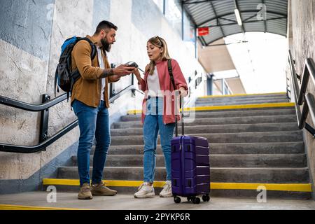 Adult couple missed the departure of the train. The are arguing at at the train station. Stock Photo