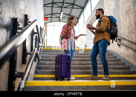 Adult couple missed the departure of the train. The are arguing at at the train station. Stock Photo