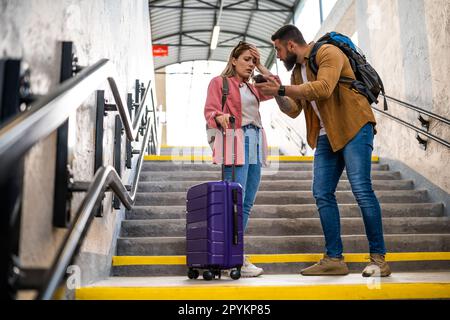 Adult couple missed the departure of the train. The are arguing at at the train station. Stock Photo