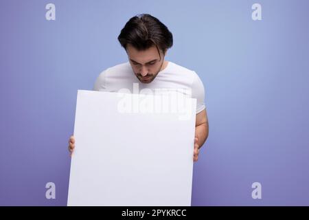young brutal brunette man shows paper poster with mockup Stock Photo