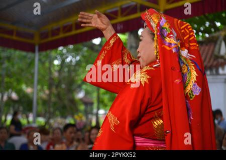 Shaman plays the role of a god performing rituals to transmit messages in Mother Goddess Worship event. Vietnam. Asia. hầu đồng. 越南旅游, 베트남 관광, ベトナム観光 Stock Photo