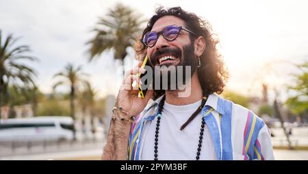 Happy hipster man speaking on the phone while walking outside in the street in summer holidays. Stock Photo