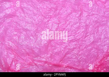 Crumpled pink plastic bag texture. Polypropylene recyclable packaging backdrop. Stock Photo