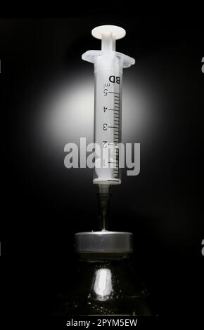 The needle of the syringe pierced the rubber membrane of the vaccine solution bottle Stock Photo