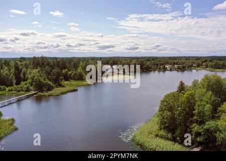 Aerial photography taken with a drone of a lake surrounded by trees in a forest during a sunny day. Aerial view of a lagoon surrounded by forest. Stock Photo