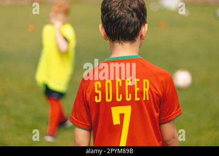 Little Soccer Boy in Red Jersey T-shirt. Schoolboy Soccer Shirt. Children Play Sports Match Outdoor. School Kid in Red Soccer Uniform Stock Photo