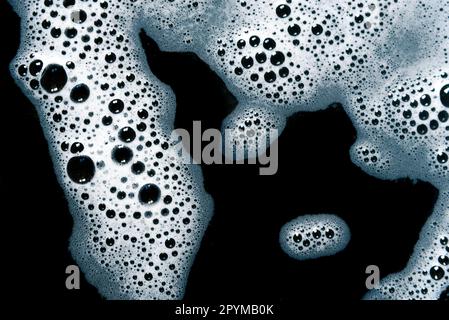 Foam air bubbles on black background. Liquid white foam from soap. Stock Photo