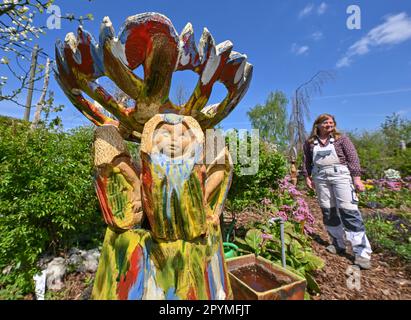 04 May 2023, Brandenburg, Sieversdorf: Undine Gomille, artist, stands next to a ceramic and prepares the garden for the 'Open Studio Days'. The first weekend in May has become a fixed date for many art lovers over the past few years. On May 06 and 07, 2023, artists will again open their studios in Brandenburg's counties and independent cities. Those who like can discover painting, graphics and book art directly at the place of origin, can look over the shoulder of sculptors and ceramic artists, learn to understand printing techniques and in some places even get the opportunity to become creati Stock Photo