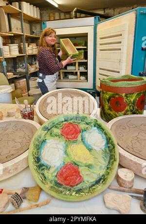 04 May 2023, Brandenburg, Sieversdorf: Undine Gomille, artist, stands in her workshop at an open kiln with ceramics and prepares the room for the 'Open Studio Days'. The first weekend in May has become a fixed date for many art enthusiasts during the past years. On May 06 and 07, 2023, artists will again open their studios in Brandenburg's counties and independent cities. Those who like can discover painting, graphics and book art directly at the place of origin, can look over the shoulder of sculptors and ceramic artists, learn to understand printing techniques and in some places even get the Stock Photo