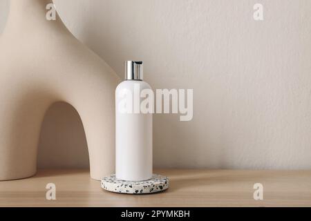 Blank white plastic bottle mockup with silver cap standing on terrazzo podium, coaster. Beige background. Face and body skin care concept. Organic Stock Photo