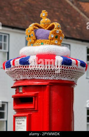 Knitted wool coronation decoration on a post box in Sawbridgeworth Hertfordshire, it features a crown and the union jack flag. Stock Photo