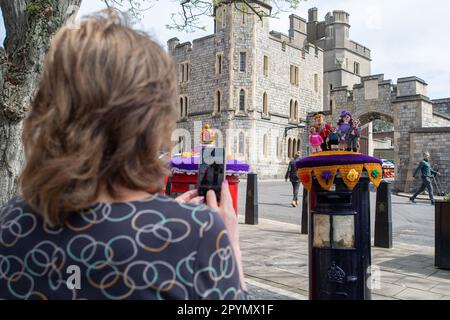 Windsor, Berkshire, UK. 4th May, 2023. Wendy Walker (L) from the All Stitched Up group of knitters in Ickenham was in Windsor this morning putting on two beautiful Coronation themed post box toppers on the post boxes outside Windsor Castle. One is a crown and the other is of the Prince and Princess of Wales with their three children Prince George, Princess Charlotte and Prince Louis. The knitters are raising money for the Brain Injury and Tumour Group Charity Shop in Hillingdon Circus. Credit: Maureen McLean/Alamy Live News Stock Photo