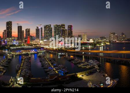 Aerial view of yachts in Miami marina at Bayside Marketplace with reflections in Biscayne Bay water and high illuminated skyscrapers of Brickell, city Stock Photo
