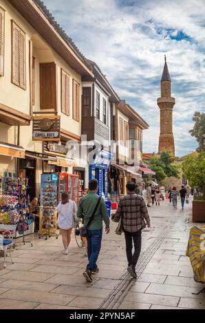 People walk down a street within Kaleici Old Town, Antalya, Antalya Province, Turkey (Turkiye) towards the famed renovated and restored Broken Minaret Stock Photo