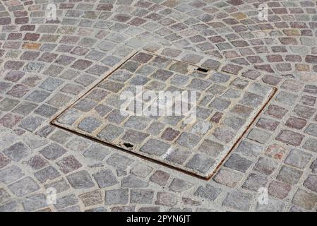 sewer hatch on cobblestone street Stock Photo