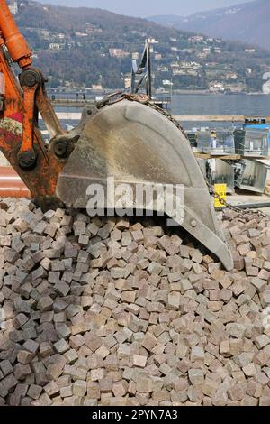 digger bucket and heap of porphyry paving stones Stock Photo