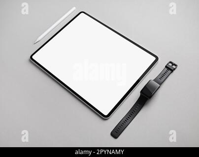 Tablet computer with blank white screen, smart watch and stylus on gray paper background. Copy space for text. Stock Photo