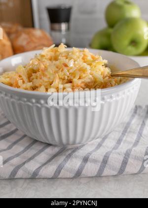 American coleslaw with white cabbage and carrots in a bowl on kitchen table background with buns Stock Photo