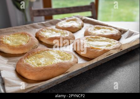Fresh baked yeast pastries with sour cream, vanilla pudding filling on a baking sheet Stock Photo