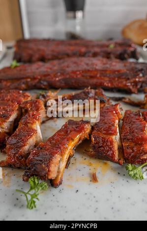 Fresh sliced pork ribs on a cutting board with whole ribs in the background Stock Photo