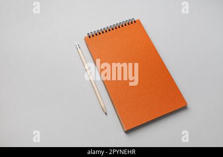 Photo of blank orange sketchbook and pencil on gray paper background. Stock Photo