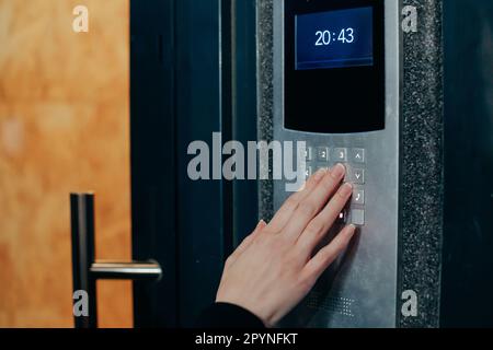 Woman hand press buttons on video intercom at entrance of apartment building in the night Stock Photo