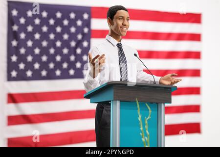 Happy young african american man on a pedestal giving a speech in front of a USA flag Stock Photo