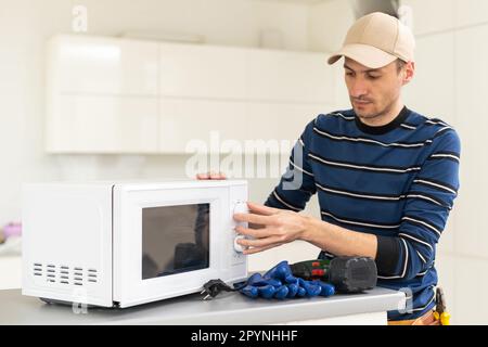 man repairing microwave. a worker repairs a microwave oven. Stock Photo
