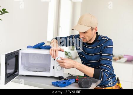 man repairing microwave. a worker repairs a microwave oven. Stock Photo