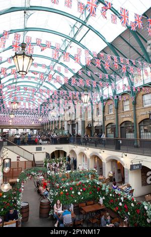 London, UK. 4th May, 2023. Union Jack bunting makes Covent Garden market extra photogenic for tourists ahead of the Coronation of King Charles III on Saturday 6 May. Credit: Anna Watson/Alamy Live News Stock Photo