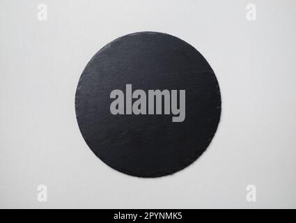 Photo of round slate plate on gray paper background. Copy space. Flat lay. Stock Photo