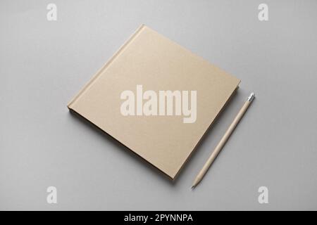 Photo of closed blank kraft brochure and pencil on gray paper background. Template for placing your design. Stock Photo