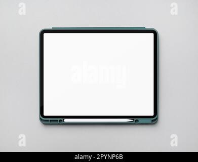 Photo of modern touch tablet with blank white screen and stylus on gray paper background. Modern work tools of designer. Flat lay. Stock Photo