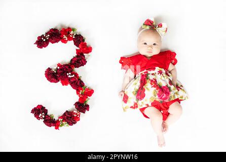 Little newborn baby girl in red dress. 3 month old baby Stock Photo