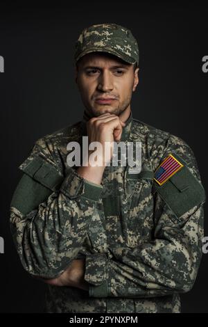 American soldier in camouflage uniform and cap suffering from ptsd isolated on black,stock image Stock Photo