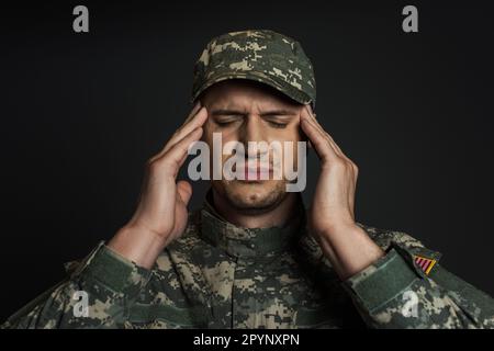 patriotic soldier in camouflage uniform and cap suffering from ptsd isolated on black,stock image Stock Photo