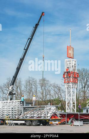 Workers using a crane to unload heavy (free fall tower) parts for the upcoming May carnival (Maikerwe) event on the Messeplatz fairground in Kaisersla Stock Photo