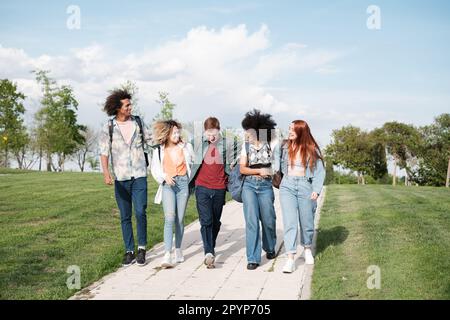 Group of students walking through the university campus having a conversation outdoors. Concept: lifestyle, friends, education Stock Photo