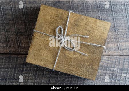 Dark wood box with a rope on a wooden background, close-up Stock Photo