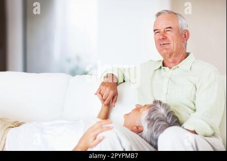 Relaxed mature couple on sofa. Portrait of happy mature couple relaxing together on couch at home. Stock Photo