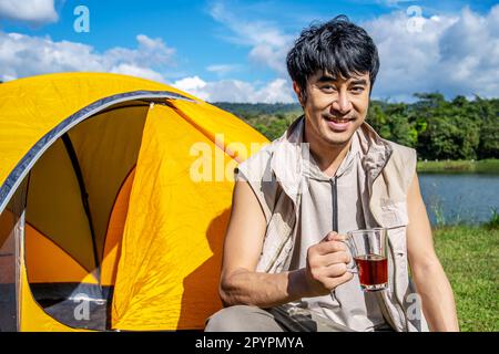 Young asian man relax travel nature in the holiday, camping and drinking coffee after boiling water, he camping on holiday. Stock Photo