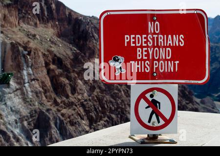 Nevada. Hoover dam. Humorous sign saying no pedestrians beyond this point. The sign sits on the concrete walkway barrier overlooking the dam. Stock Photo
