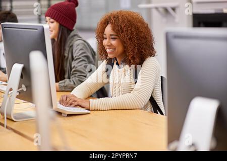 Using technology to her advantage in her studies. students working on computers in a university library. Stock Photo
