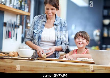 The secret ingredient is always happiness. a mother and daughter baking together in the kitchen. Stock Photo