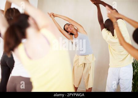 Working up a sweat. A pretty yoga instructor showing her class how to perform a routine. Stock Photo