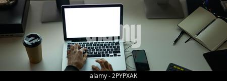 Work anytime. High angle view of hands of man sitting at the table in front of many computer monitors and using laptop while working late at night Stock Photo